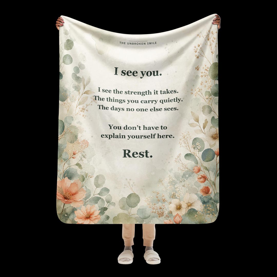 Flare Day Comfort Blanket, a 50 by 60 sherpa throw with watercolor florals, shown on a couch with the Color Your Calm coloring book